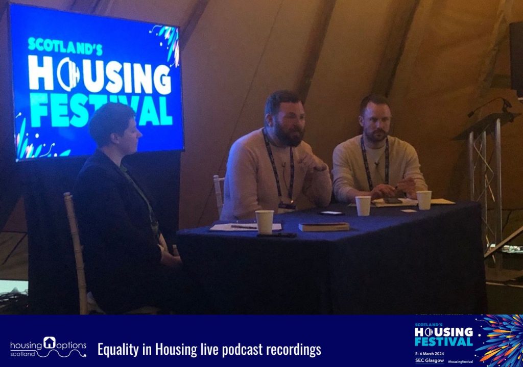 Photo of three people sat in front of a screen. Caption reads Equality in Housing live podcast recording